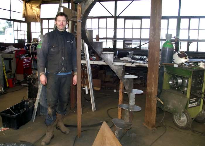 Alexandre sotty dans son atelier au milieu de sa ferraille